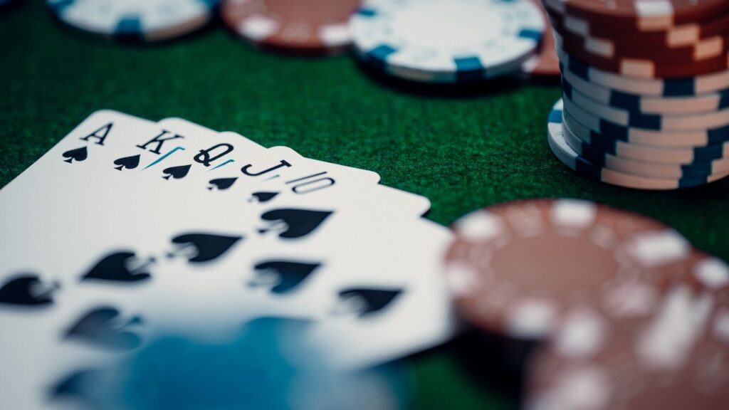 Close-up of a royal flush poker hand surrounded by colorful chips on a green table.